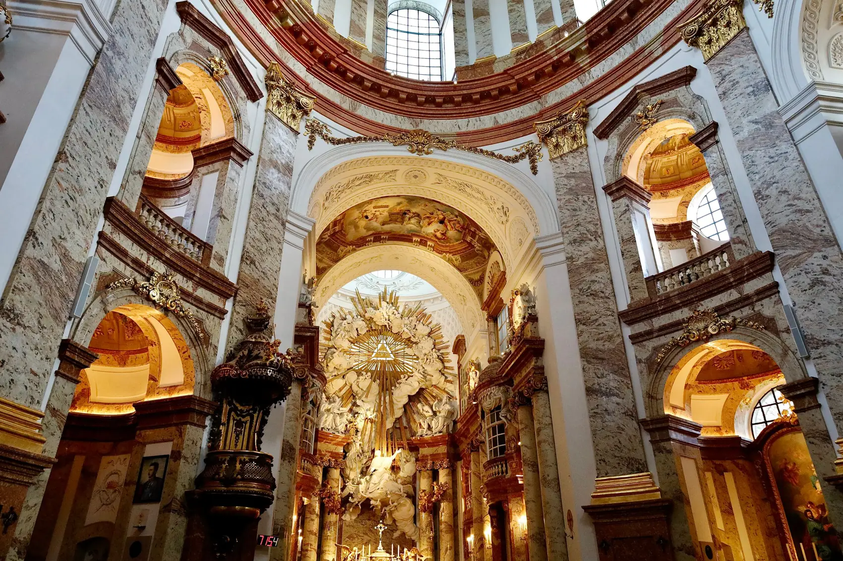 Uvnitř Karlskirche se bledé mramorové sloupy tyčí k kupoli nad pozlaceným hlavním oltářem